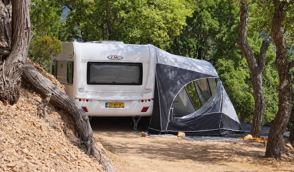 Une caravane avec son auvent à l’ombre des arbres — Emplacement Terrasse, Camping Les Philippons