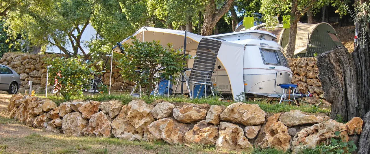 Wohnwagen und Zelte auf den schattigen Stellplätzen und Steinterrassen von Camping Les Philippons